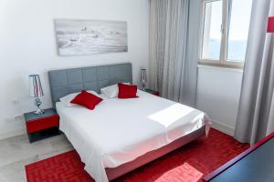 - une chambre avec un grand lit blanc et des oreillers rouges dans l'établissement Lustica Bay Marina Village 3-bedroom corner apartment with a terrace and panoramic sea view, à Radovići