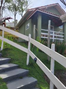 uma cerca branca em frente a uma casa em Pousada Recanto João de Barro em Cunha