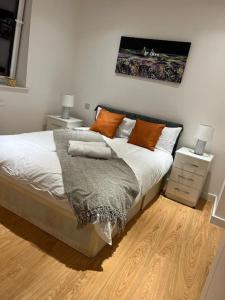 1 dormitorio con 1 cama grande con almohadas de color naranja en Modern 2 Bedroom Flat TH132 en Basildon