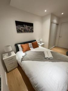 バジルドンにあるModern 2 Bedroom Flat TH132のベッドルーム(オレンジ色の枕が付いた大きな白いベッド付)