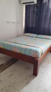 a small bed in a room with a blue curtain at HOTEL LA CORDIALIDAD in Barranquilla