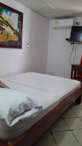 a white bed in a room with a painting on the wall at HOTEL LA CORDIALIDAD in Barranquilla