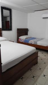 een slaapkamer met 2 bedden en een spiegel bij HOTEL LA CORDIALIDAD in Barranquilla