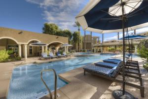a swimming pool with lounge chairs and an umbrella at Luxury Vacation Rentals by Meridian CondoResorts in Scottsdale