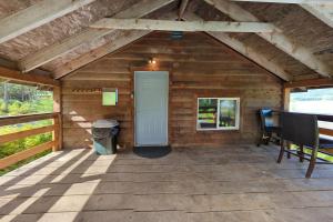 a porch of a wooden cabin with a white door at Whale Pass Adventure Apartment 