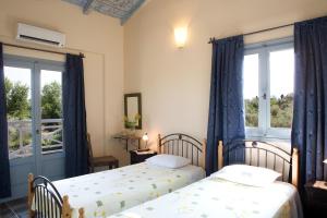 two beds in a room with two windows at Villa Simeoni in Lefkada +12 photos