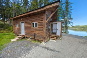 Cabaña de madera pequeña con puerta y escaleras junto a un lago en Whale Pass Adventure Cabin, 