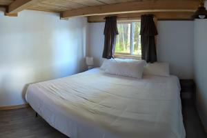 1 dormitorio con 1 cama blanca grande y ventana en Whale Pass Adventure Cabin, 