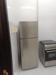 lodówka ze stali nierdzewnej w kuchni obok kuchenki w obiekcie شقق الاحلام الذهبية 