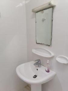W białej łazience znajduje się umywalka i lustro. w obiekcie شقق الاحلام الذهبية 