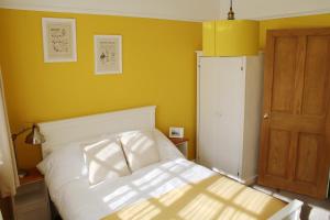 - une chambre avec un lit blanc et un mur jaune dans l'établissement Charming 1800s Port Sunlight Worker's Cottage, à Port Sunlight