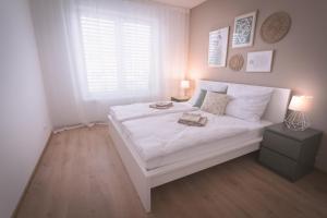 Un dormitorio con una gran cama blanca y una ventana. en Nový štýlový byt, blízko letiska, en Bratislava