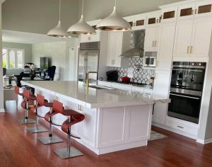 a kitchen with white cabinets and a counter with red chairs at 2-Acre Highland Park Retreat with Heated Pool ~ 5* in Highland Park