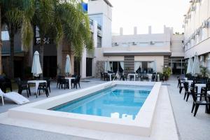 a swimming pool with tables and chairs next to a building at Hotel Termasol in Termas de Río Hondo