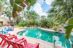 a swimming pool with red chairs and palm trees at Casa Rayo de Sol - Private ranch guest home in Mission