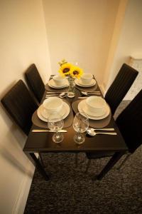 a table with plates and glasses and flowers on it at Spacious Sea-View Flat w SmartTV in Lowestoft