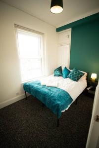 a bedroom with a bed with blue and white sheets and a window at Spacious Sea-View Flat with Easy Invest in Lowestoft