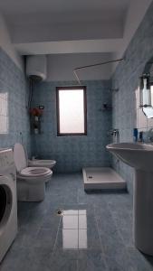 een badkamer met 2 wastafels, een toilet en een raam bij Homemaker in Berat