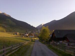 a dirt road in a village with mountains in the background at Ferienwohnung Boahof in Lessach