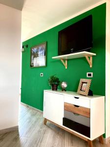 a living room with a green wall with a tv at La casita in Civitavecchia