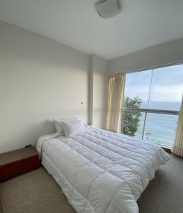 Apartamento Vista al Mar في ليما: غرفة نوم بسرير ابيض كبير ونافذة كبيرة