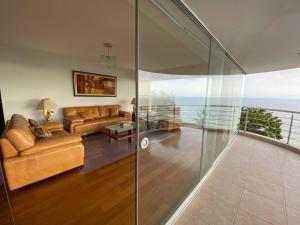 Apartamento Vista al Mar في ليما: غرفة معيشة مع أريكة وجدار زجاجي