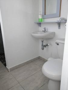 La salle de bains blanche est pourvue de toilettes et d'un lavabo. dans l'établissement Apartamento en Pereira sobre la avenida principal de la ciudad 203, à Pereira