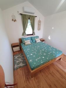 a bedroom with a bed with a green comforter and a window at Bungalov Lenka in Temerin