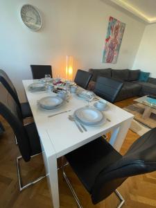 - une table à manger blanche avec des chaises et des assiettes dans l'établissement Like home2, à Belgrade