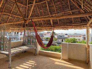 una hamaca en un porche con techo de paja y vistas en Umma House en Lamu
