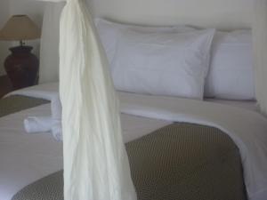 uma cama branca com lençóis e almofadas brancos em Tambun Sari Beach Homestay em Amed