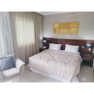 a bedroom with a large bed and a chair at Flat Super Luxo Verbo Divino in Sao Paulo