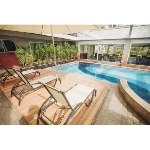 a pool with chairs and an umbrella in a building at Flat Super Luxo Verbo Divino in Sao Paulo