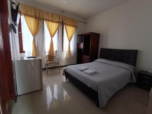 Schlafzimmer mit einem Bett, einem Stuhl und Fenstern in der Unterkunft Hotel Clasico in Manizales
