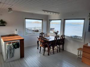 a dining room with a table and chairs and windows at Cabin at the sea. public beach close with jumpingtower. in Höviksnäs