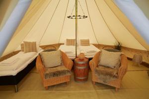 Tienda con 2 sillas, mesa y cama en Sandtorgholmen Glamping, en Sandtorv