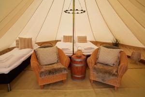 Zelt mit 2 Stühlen, einem Tisch und einem Bett in der Unterkunft Sandtorgholmen Glamping in Sandtorv