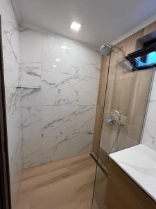 a bathroom with a shower with white marble walls at Guest House EGO in Bratsigovo