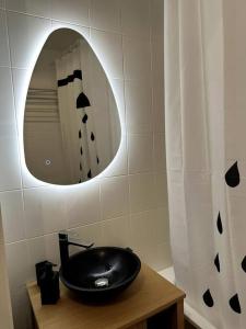 W łazience znajduje się czarna umywalka i lustro. w obiekcie Studio JadOr gare du Bourget Paris aeroport Charles de Gaulle w mieście Le Bourget
