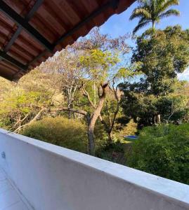 uma varanda com vista para árvores e arbustos em Loft do Sítio São José em Petrópolis