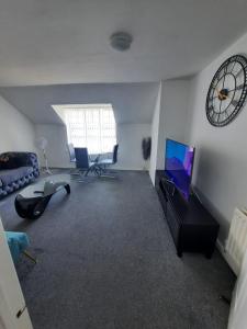 - un salon avec une télévision et une horloge murale dans l'établissement River View Two Bed Room Luxury Apartment, à Thamesmead
