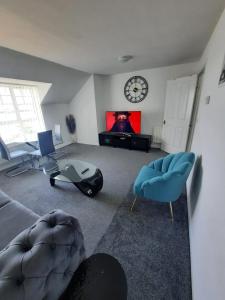 a living room with a tv and chairs and a clock at River View Two Bed Room Luxury Apartment in Thamesmead