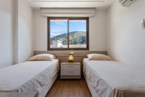 twee bedden in een kamer met een raam bij Cobertura exclusiva com Jacuzzi Privativa no Coração de Itaipava in Itaipava