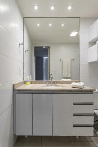 ein Badezimmer mit Waschbecken und großem Spiegel in der Unterkunft Cobertura exclusiva com Jacuzzi Privativa no Coração de Itaipava in Itaipava