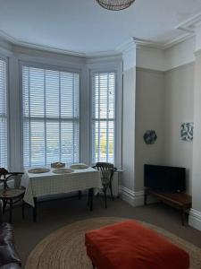 a living room with a table and some windows at Pier View Felixstowe - Sea View, 50m from the beach in Felixstowe