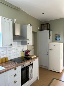 a kitchen with white cabinets and a white refrigerator at Pier View Felixstowe - Sea View, 50m from the beach in Felixstowe