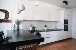 a kitchen with a black table and white cabinets at Prague Marina River View Apartment Close To City Centre FREE PARKING in Prague