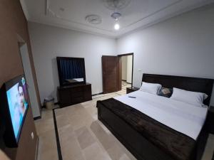 a bedroom with a bed and a flat screen tv at Islamabad Layover Guest House Free Airport Pick and Drop in Islamabad