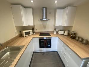 a kitchen with white cabinets and a microwave at Igloo ViewPoint II City Centre Retreat + Parking in Sheffield