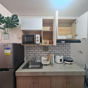 a kitchen with a sink and a microwave at HOMELY @ Green 2 Residences SMDC DLSUMC in Dasmariñas